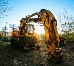 yellow excavator on dirt ground near bare trees during daytime